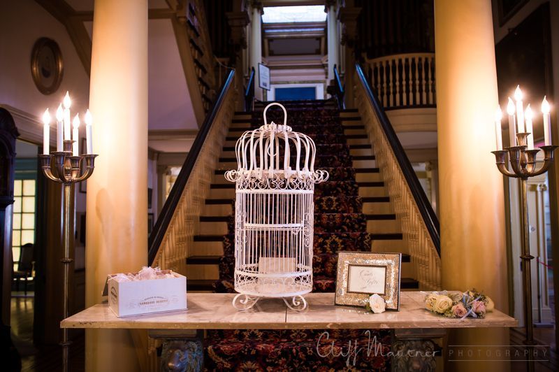 A bird cage is sitting on a table in front of a staircase.