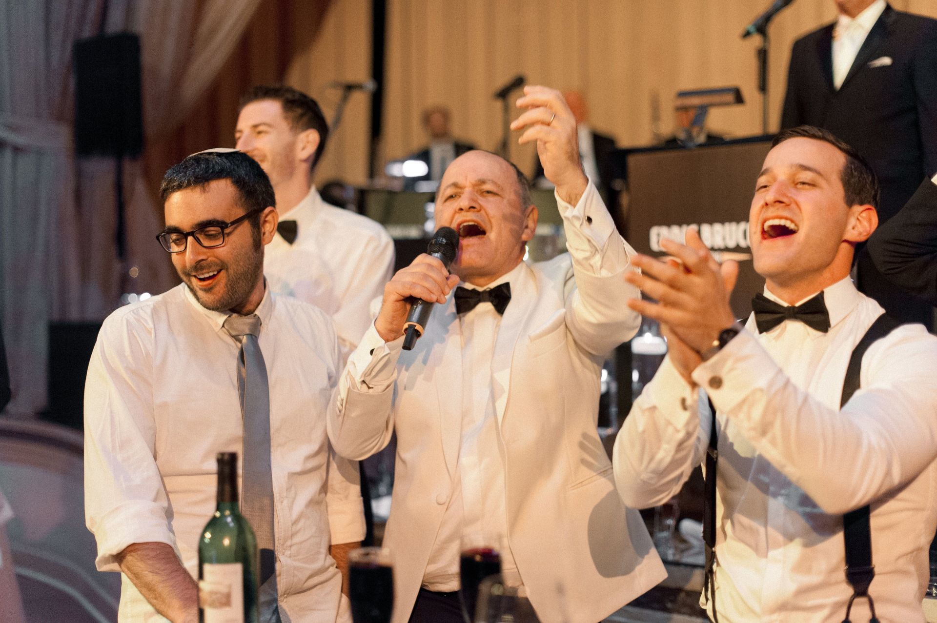A group of men in tuxedos are singing into microphones.