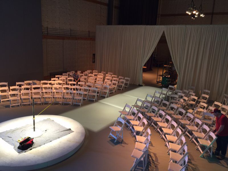 Rows of folding chairs are arranged in a circle on a stage