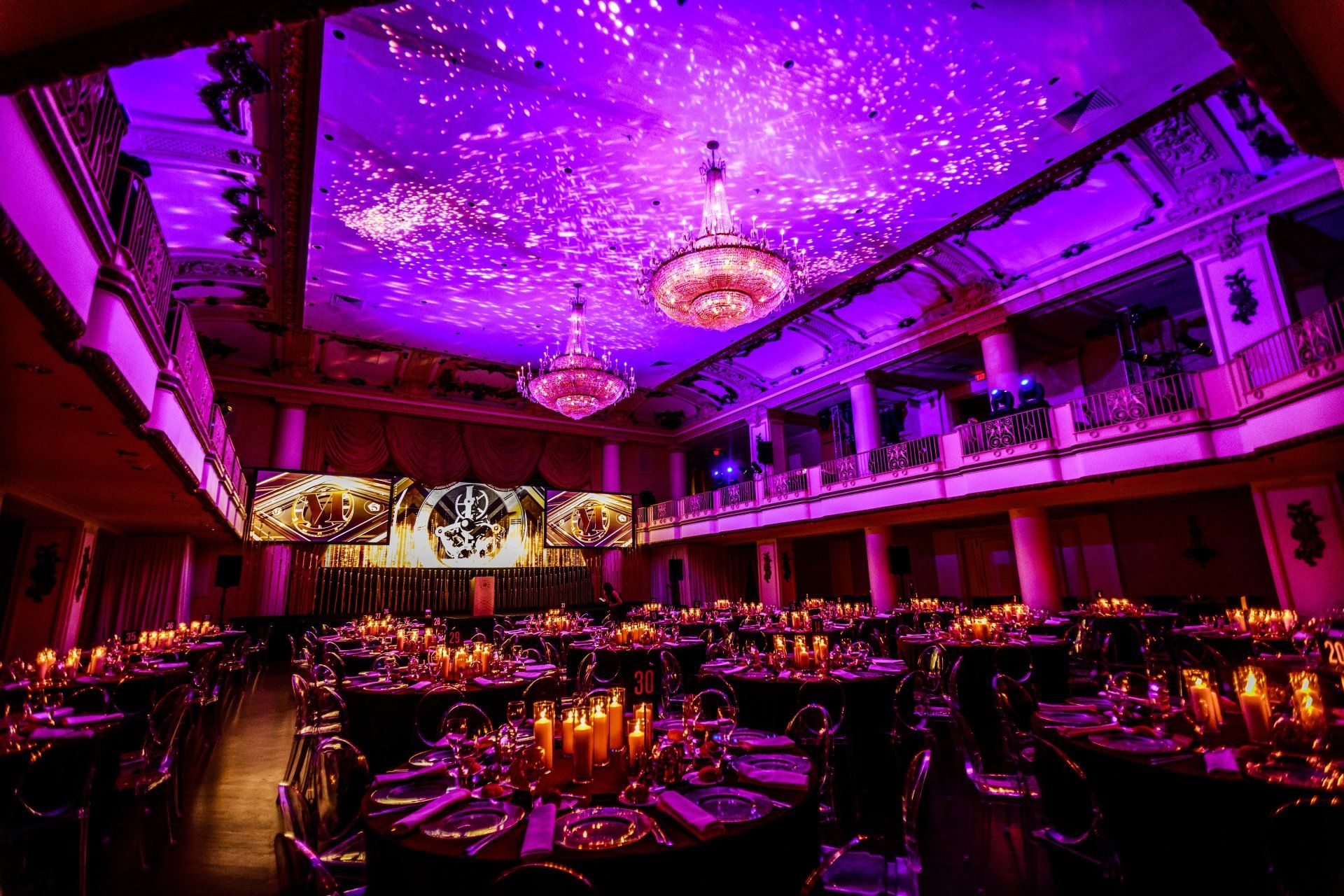 A large room filled with tables and chairs with purple lights on the ceiling.