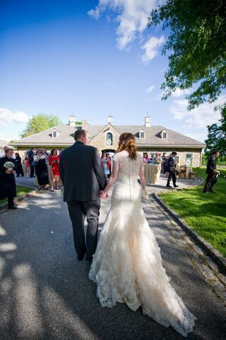 A bride and groom are walking down a path holding hands.