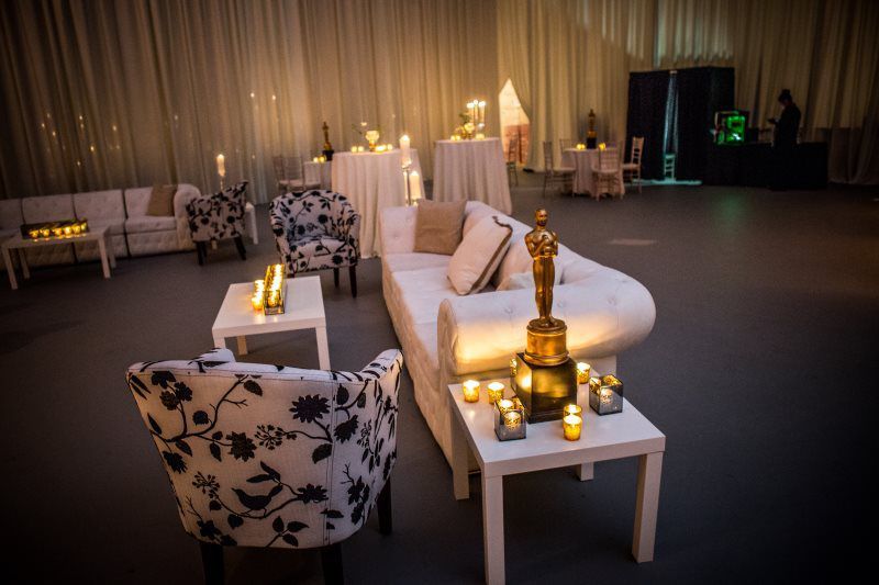 A room with a couch , chairs , tables and a statue of an oscar.