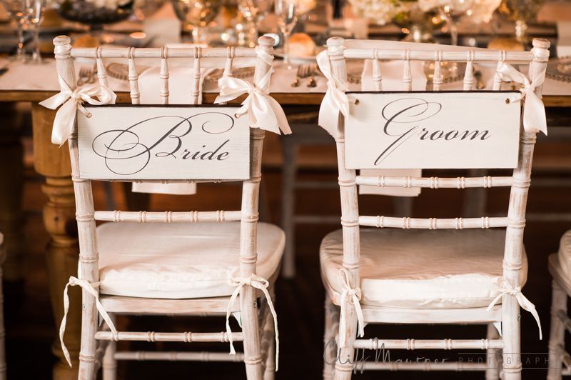 A bride and groom chair with signs on the back of them.