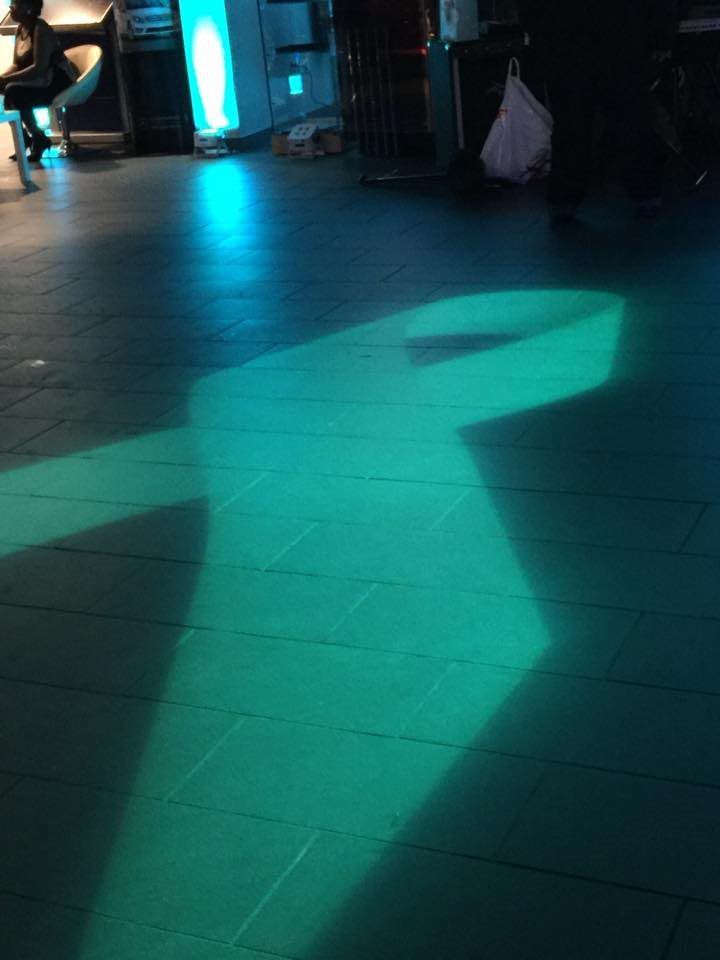 A shadow of a person is cast on a tiled floor