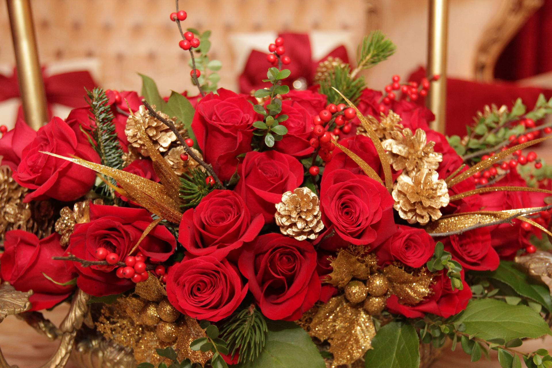 A bouquet of red roses and gold decorations on a table.