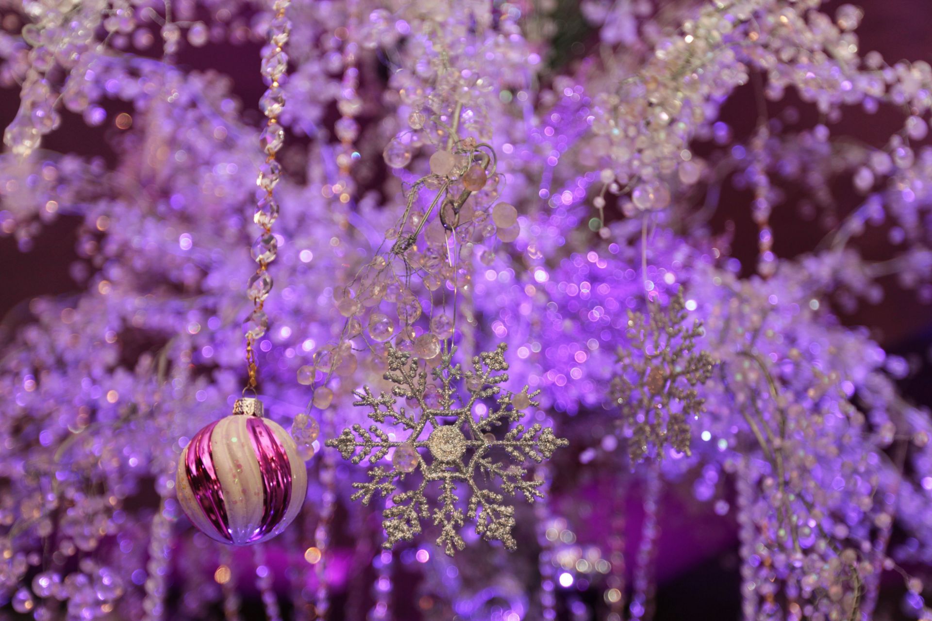 A close up of a christmas tree with purple lights and decorations.