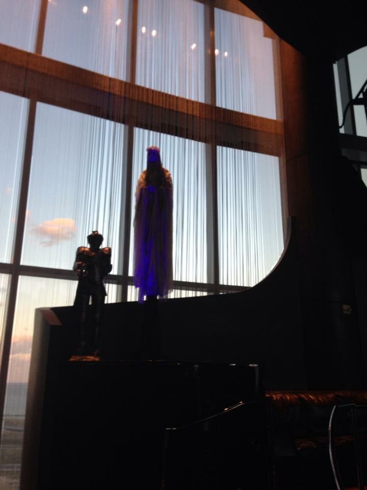 A statue of batman stands in front of a large window