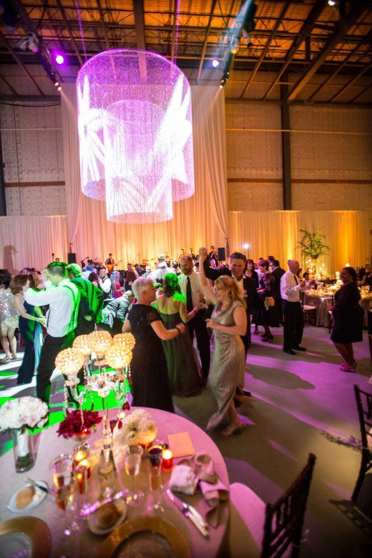 A large group of people are dancing at a wedding reception.
