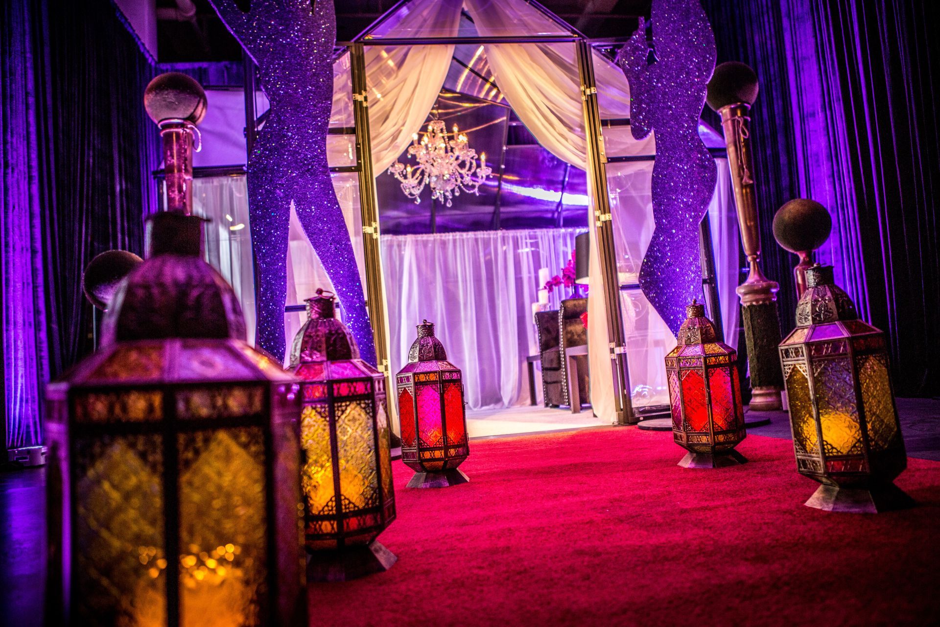 A row of lanterns are lined up on a red carpet in a room.