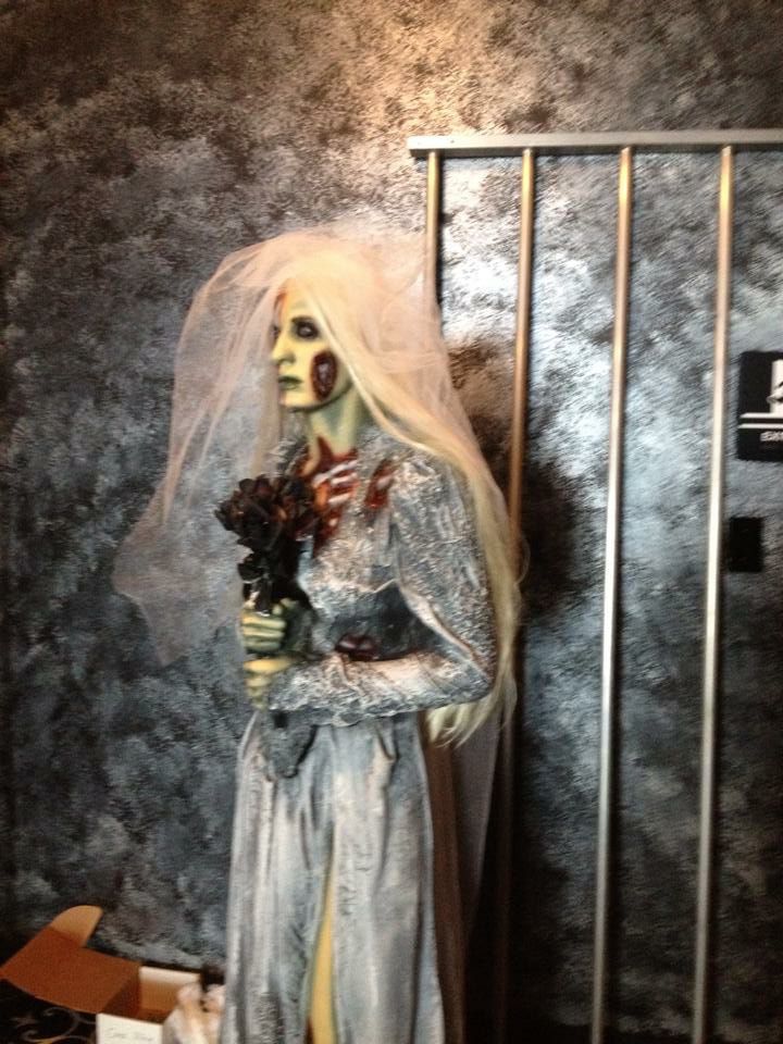 A mannequin dressed as a zombie bride is holding a bouquet of flowers.