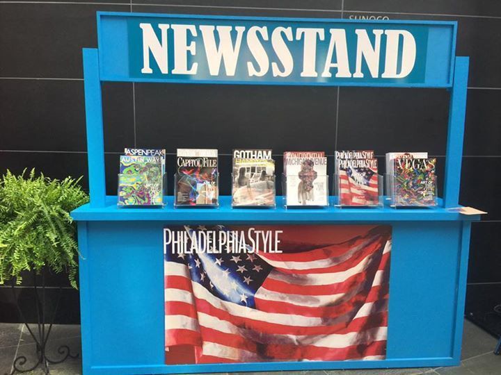 A blue newsstand with magazines and an american flag