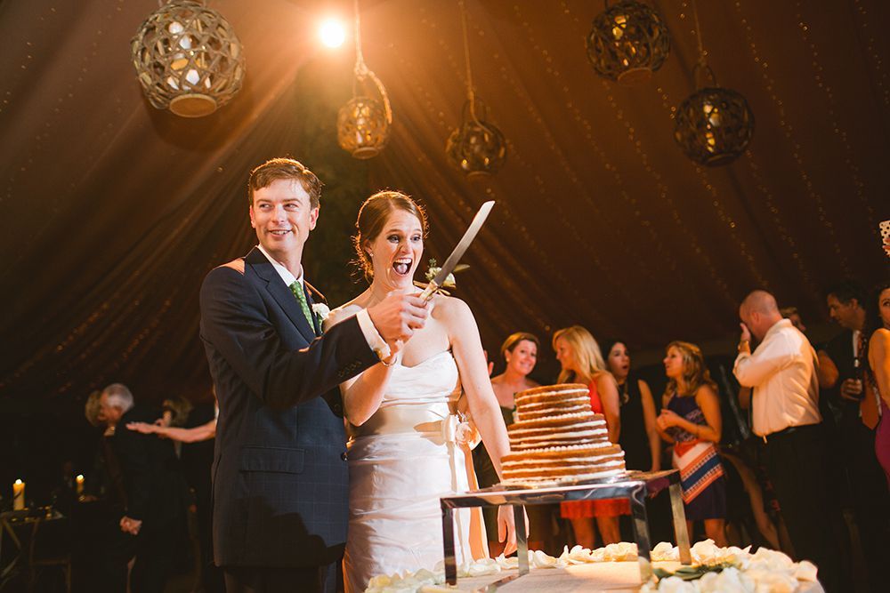A bride and groom are cutting their wedding cake together.