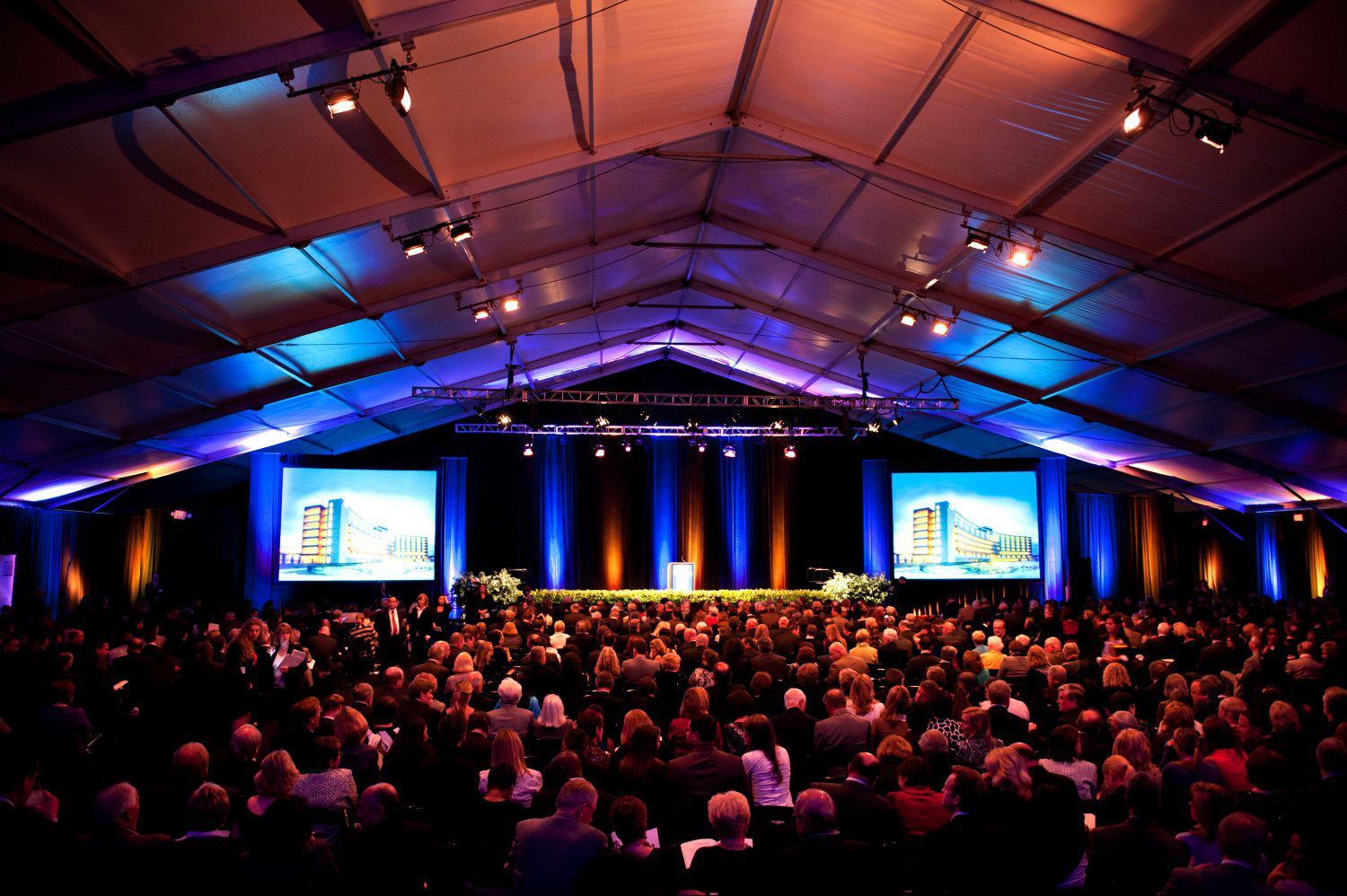 A large crowd of people are watching a presentation in a tent