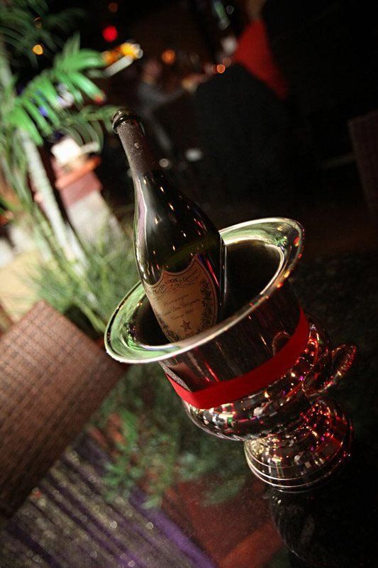 A bottle of champagne is in an ice bucket with a red ribbon.