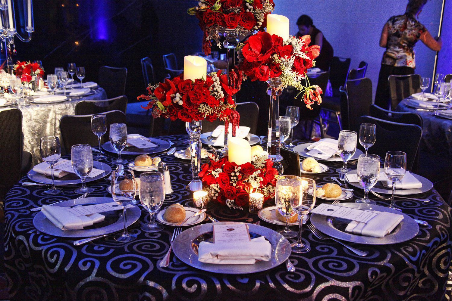 A table set for a dinner party with red flowers and candles