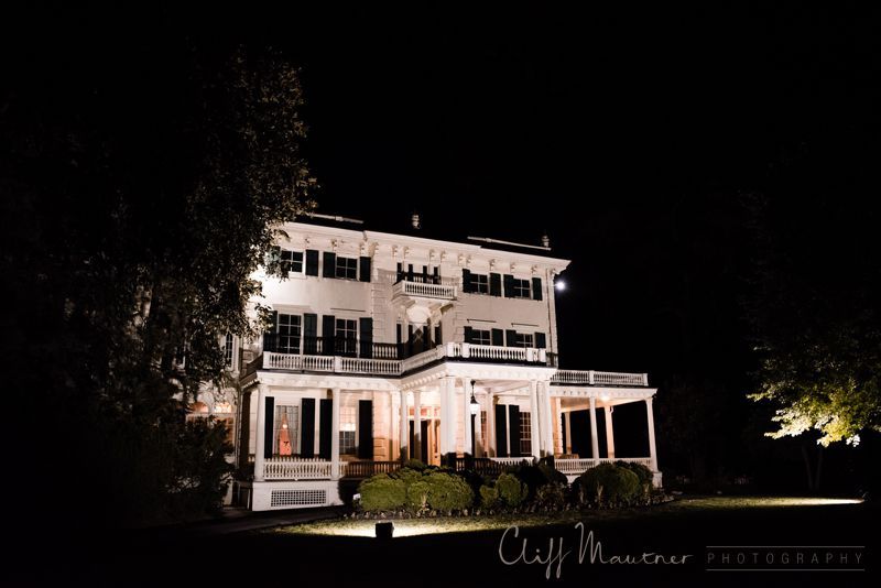 A large white house is lit up at night.