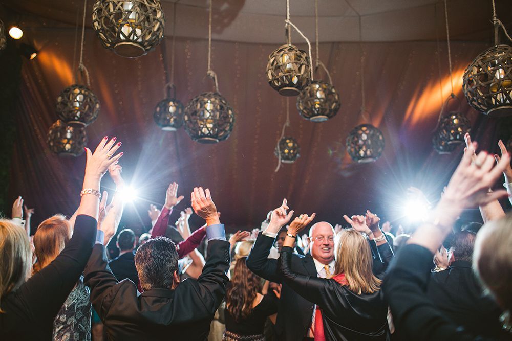 A group of people are dancing in a room with their hands in the air.