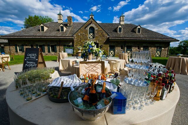 A table with a lot of glasses and bottles on it in front of a building.