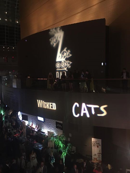 A wicked and cats sign is lit up in a dark room