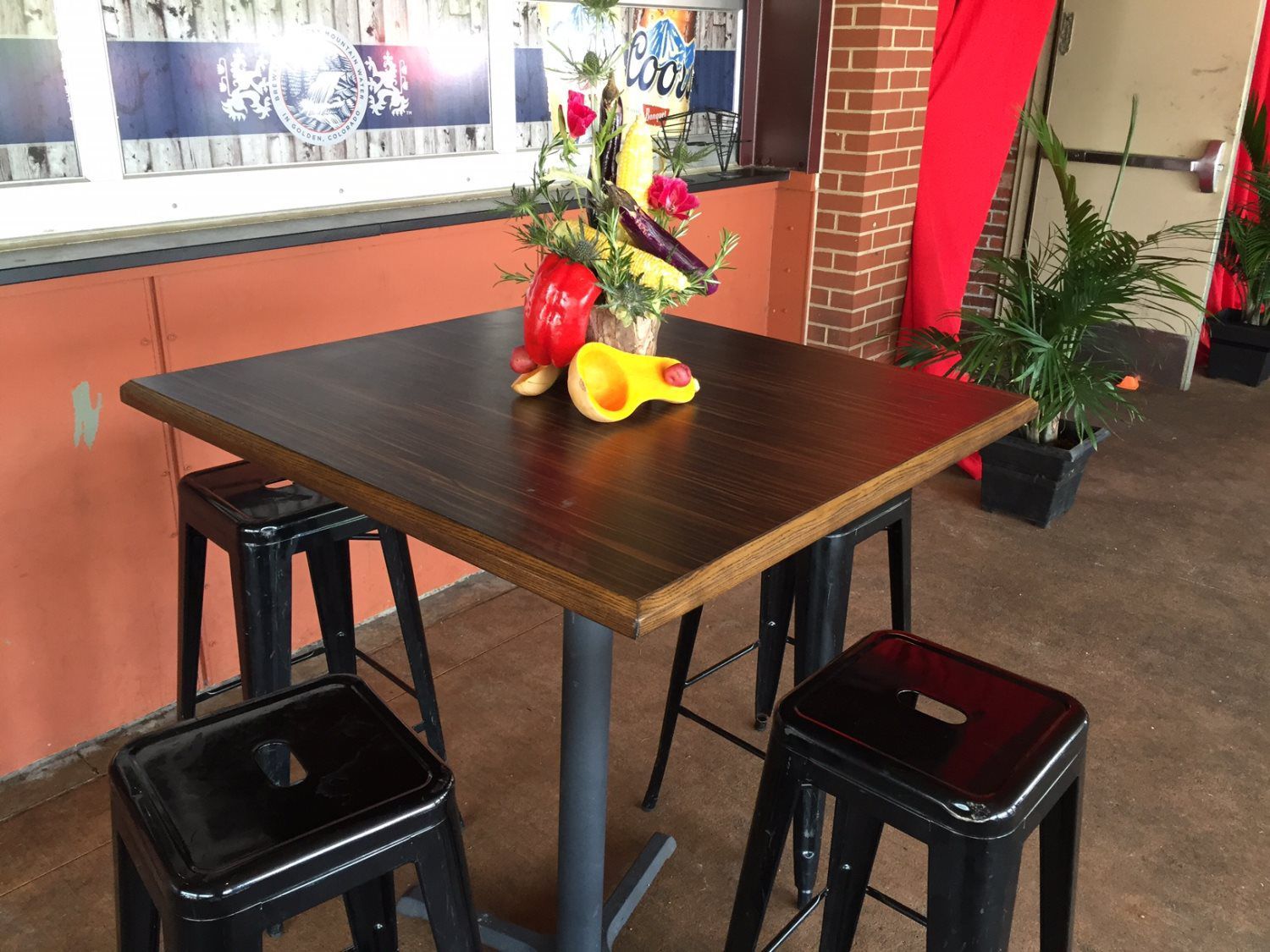 A table with stools and a vase of fruit on it