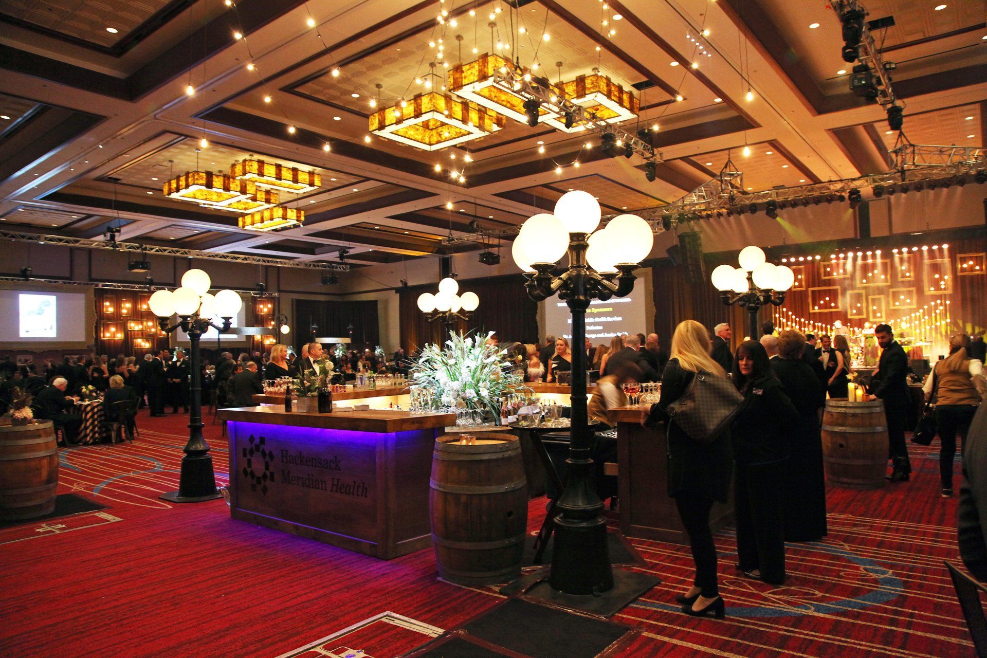 A large room with people standing around a bar and barrels