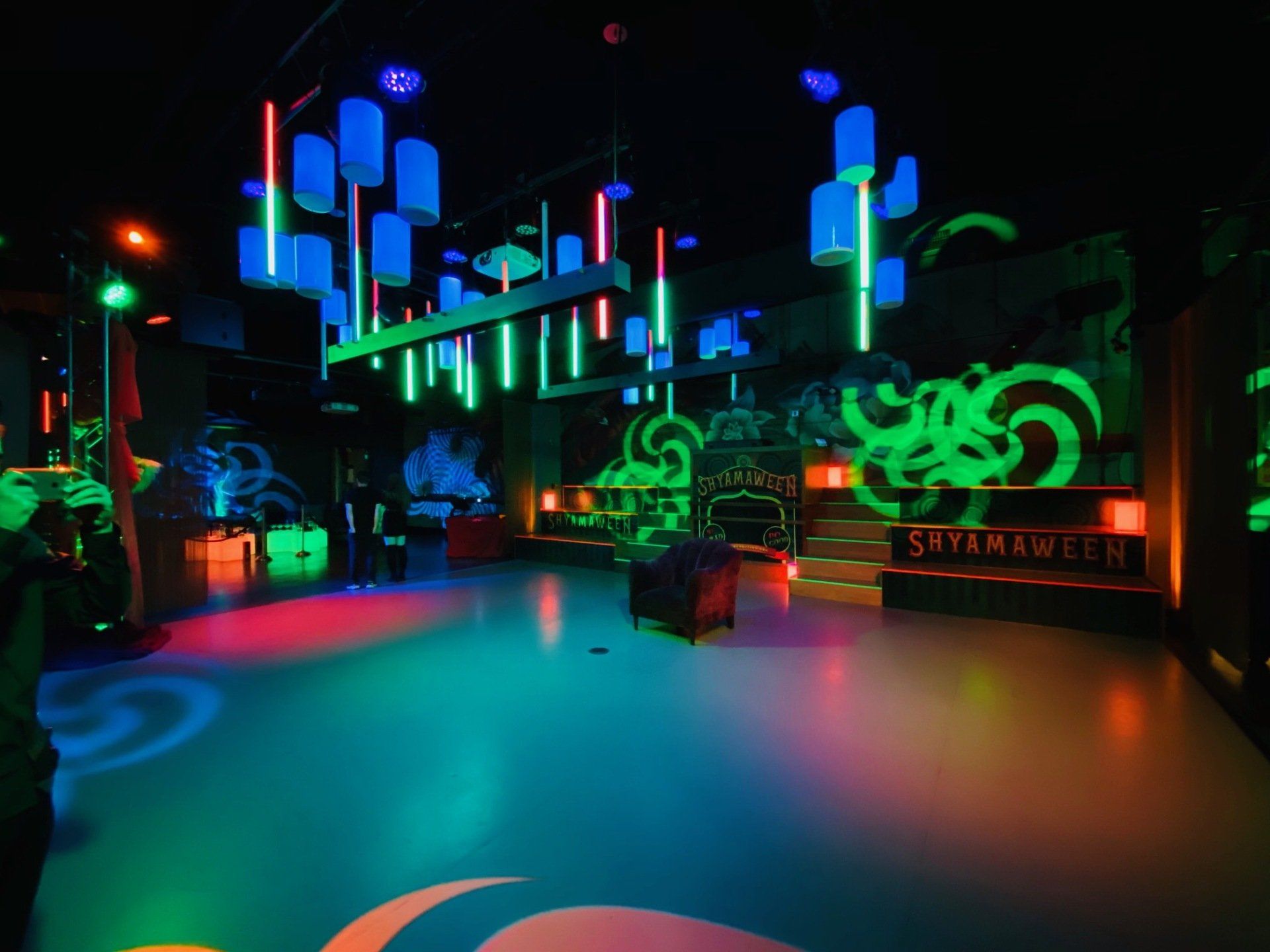 A dark room with neon lights and a sign that says suyamawen