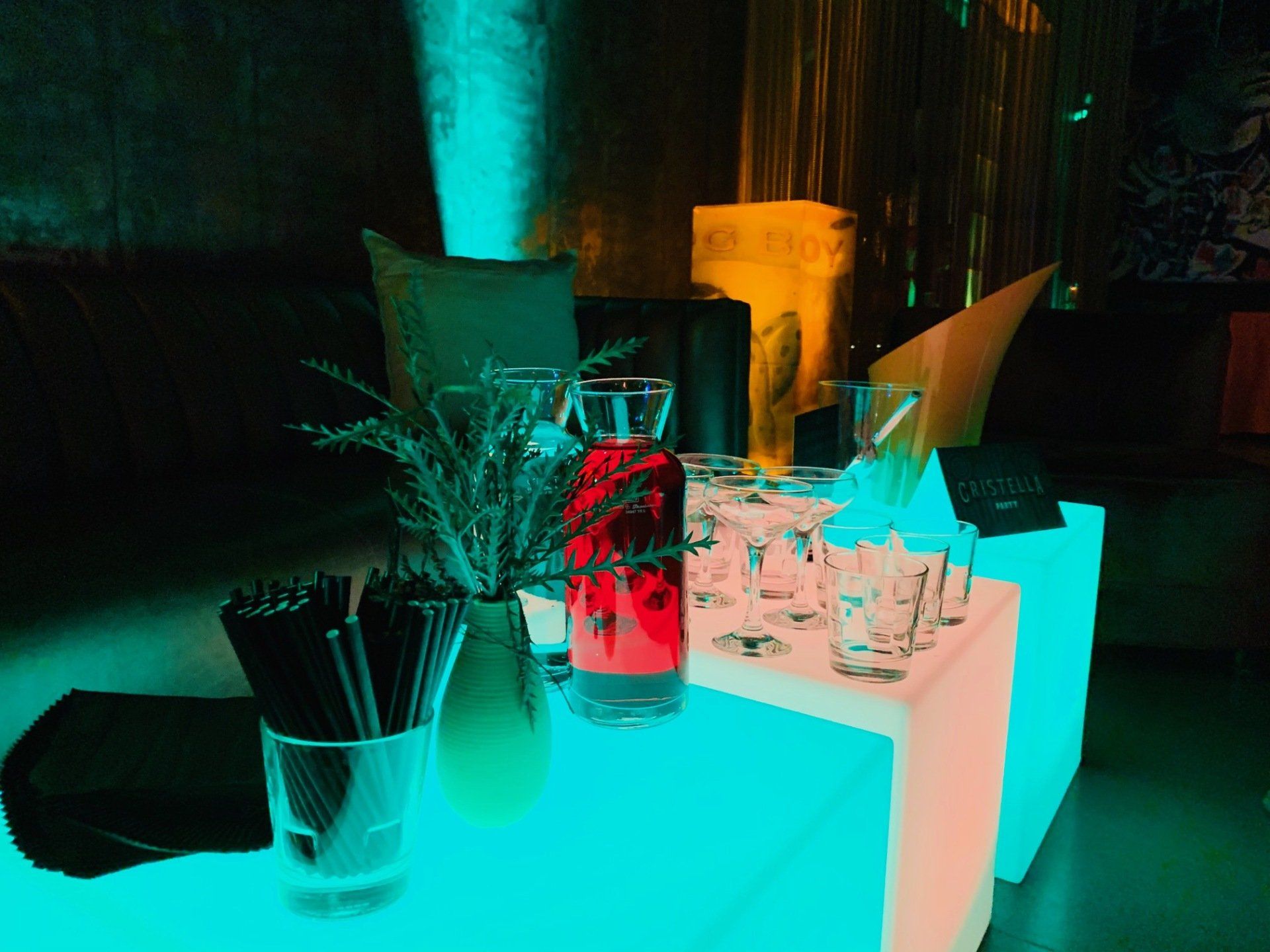 A table with a bottle of red liquid and glasses on it