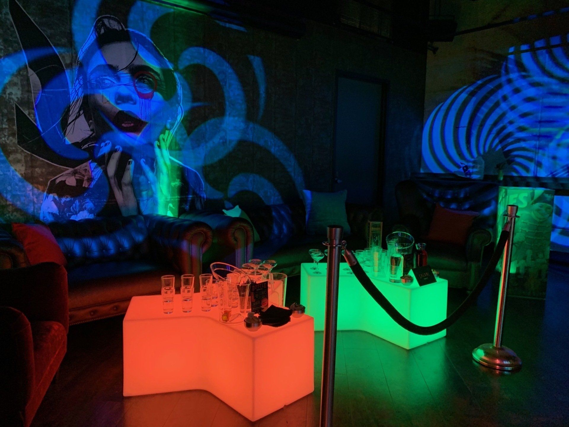 A room with glow in the dark tables and a rope barrier.