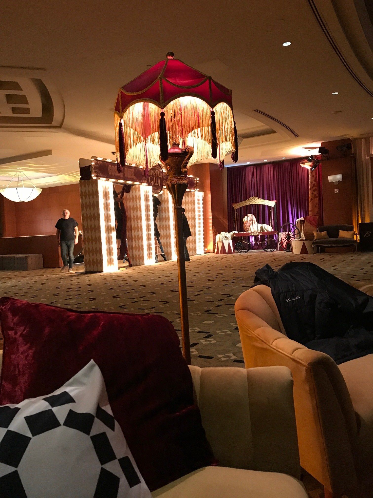 A lamp is sitting in the middle of a room with chairs and pillows.