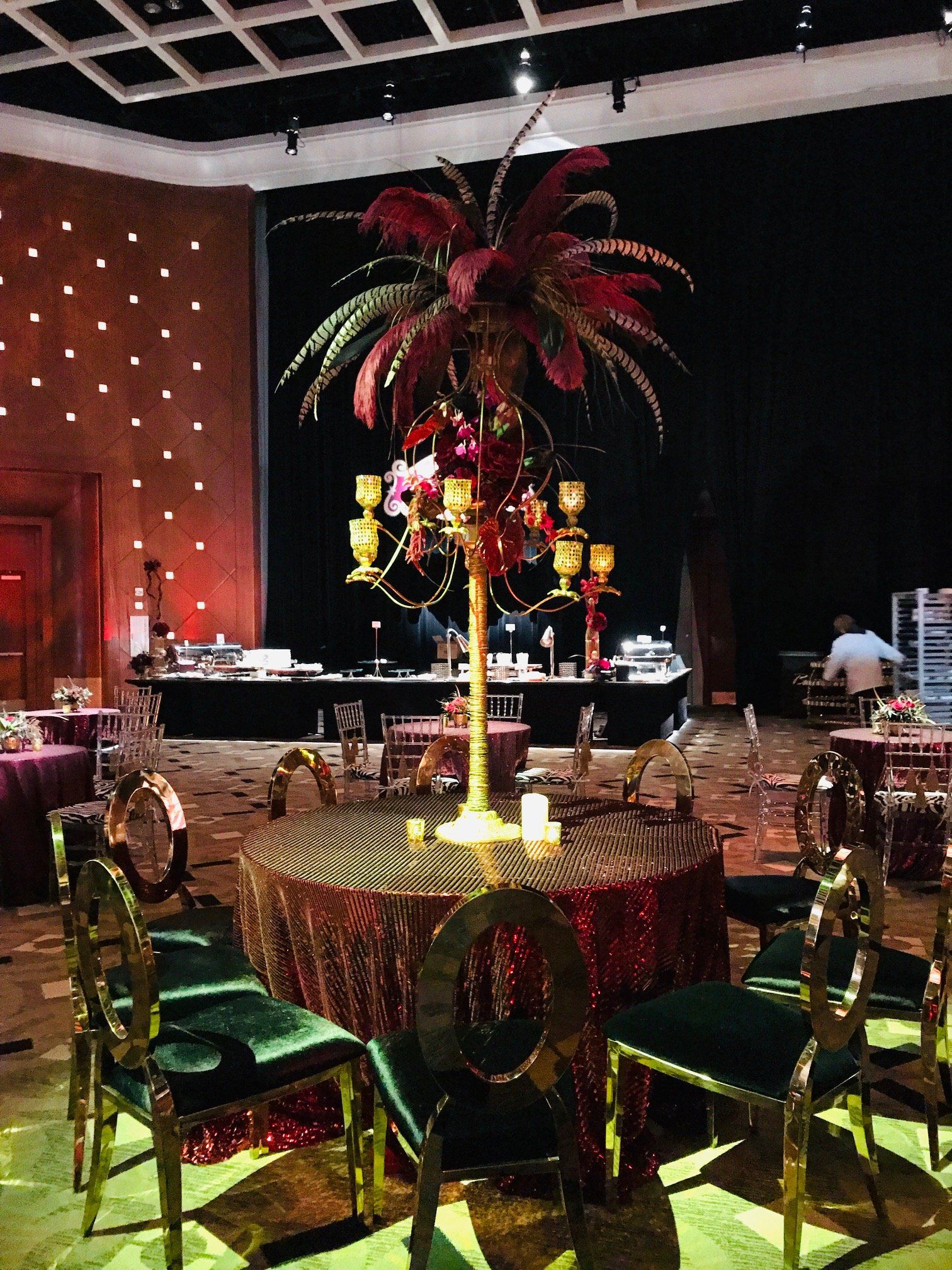 A large room with tables and chairs and a candelabra with flowers on it.