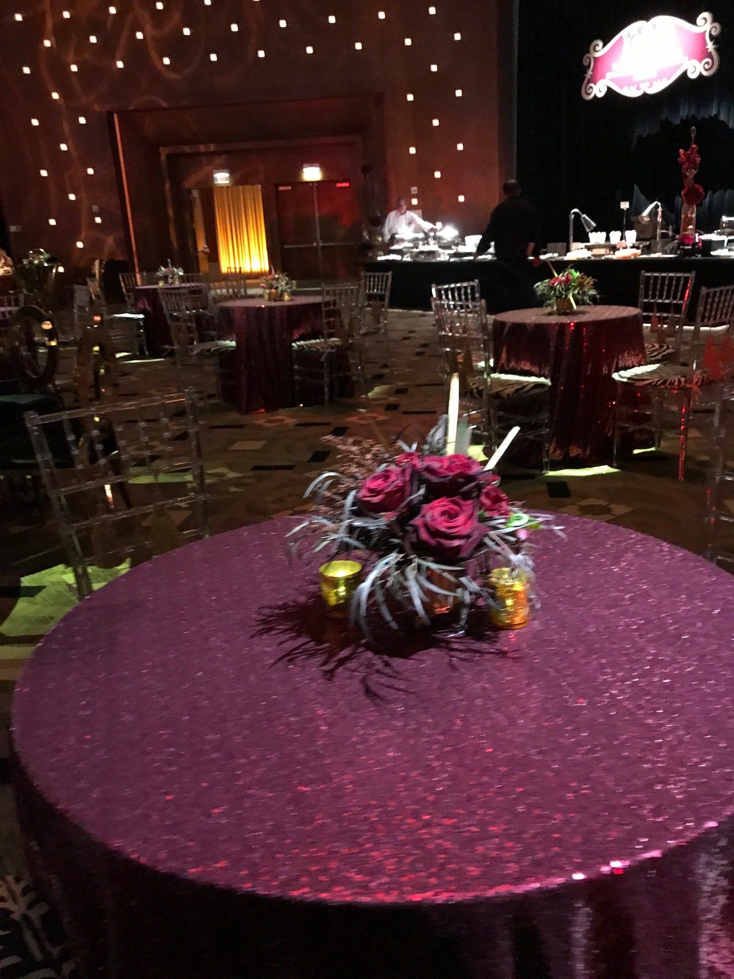 A round table with a purple tablecloth and flowers on it.
