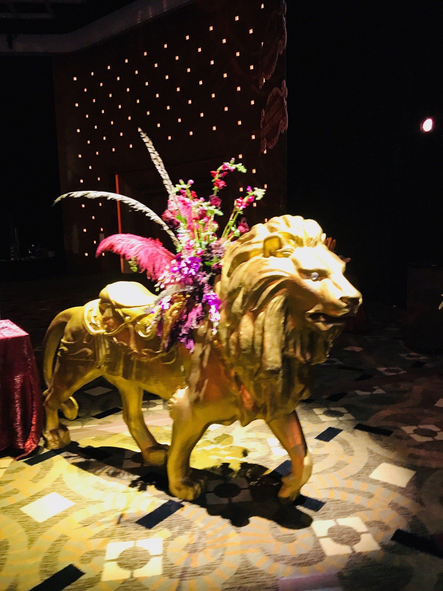 A gold statue of a lion with flowers on its back.