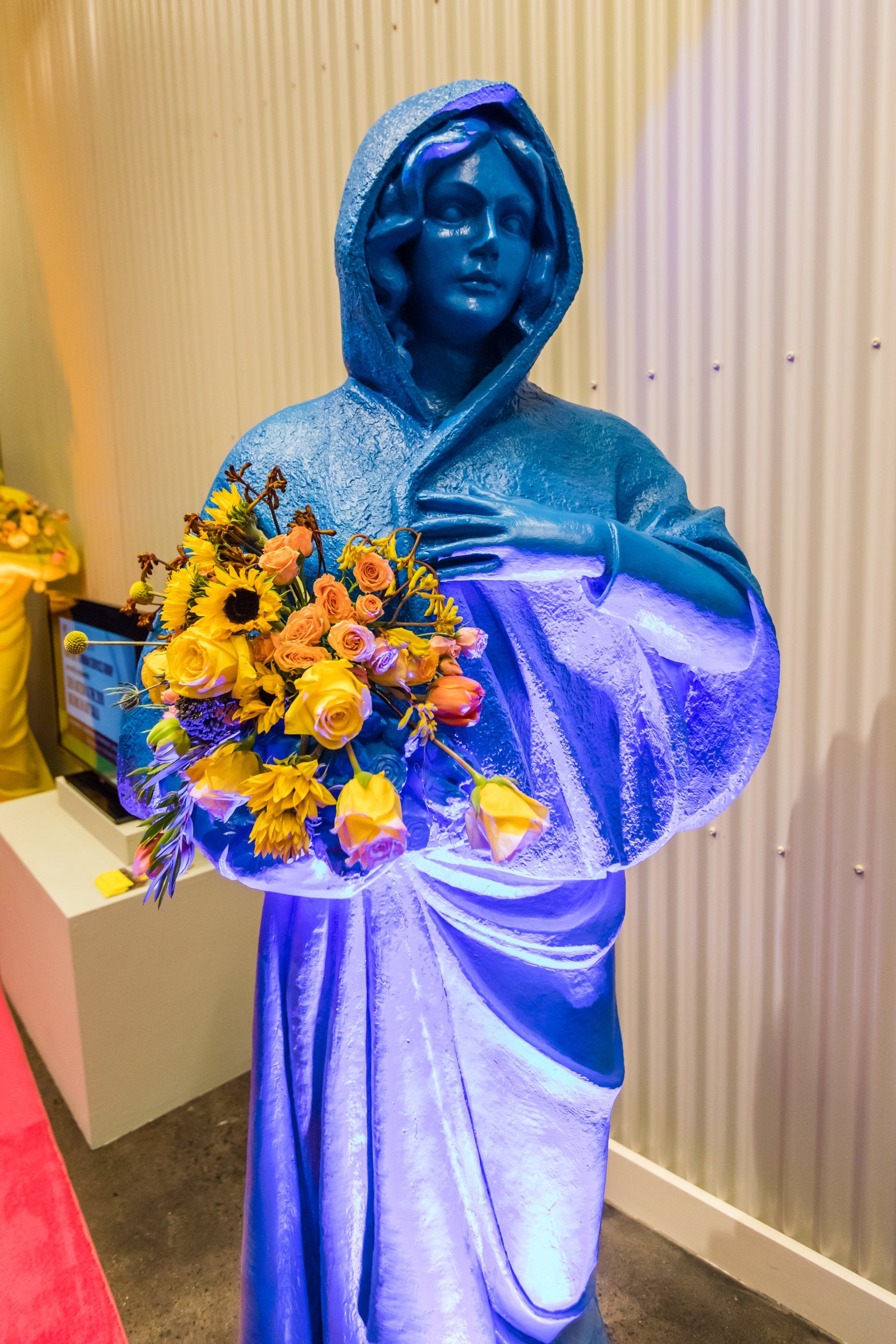 A blue statue of a woman holding a bouquet of flowers.