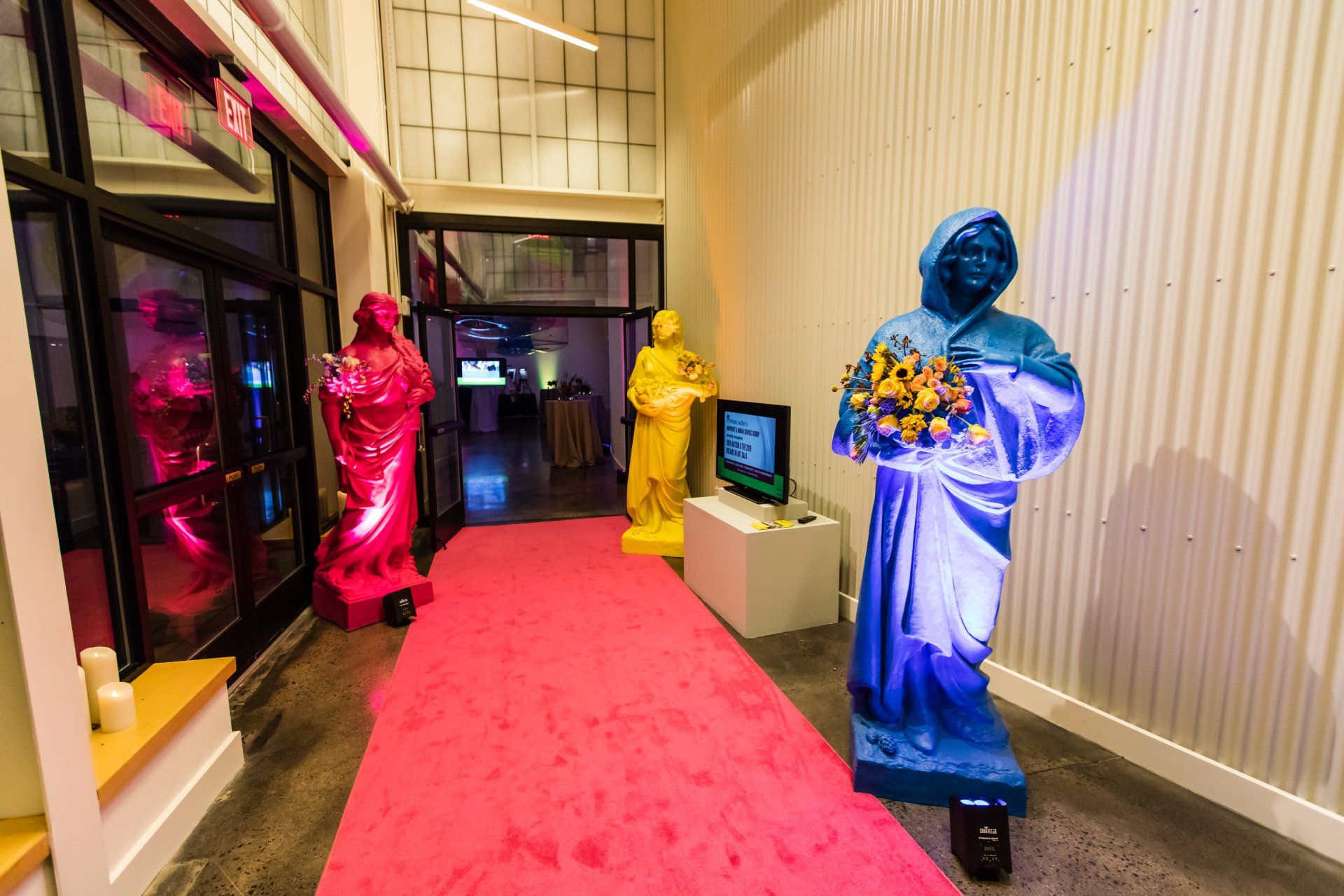 A hallway with a pink carpet and a bunch of statues