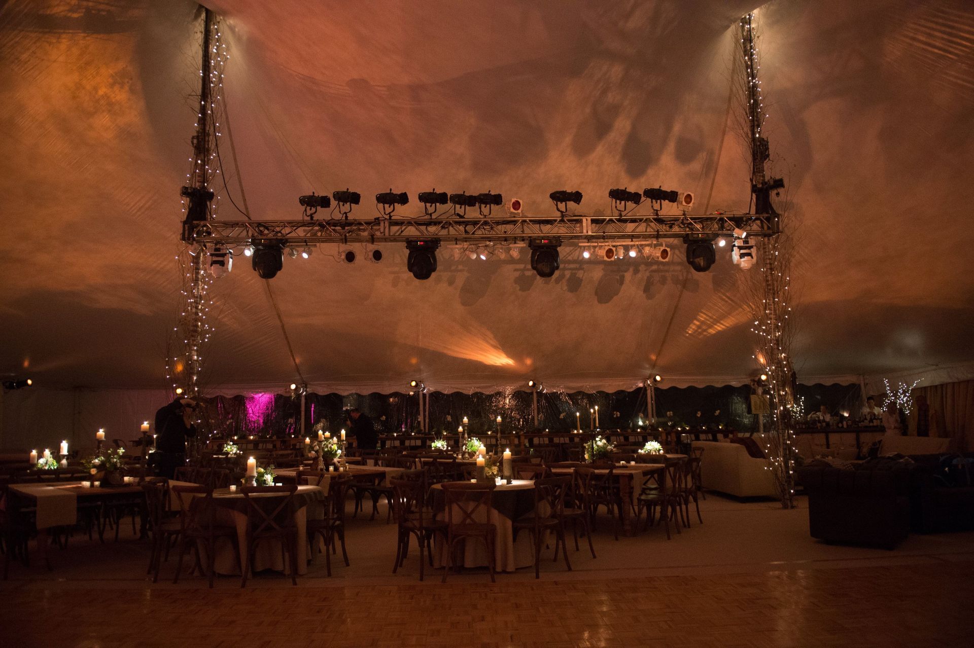 A large tent filled with tables and chairs is lit up at night.