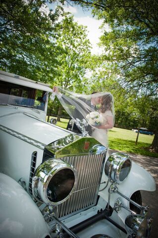 A bride and groom are posing for a picture in a white car.