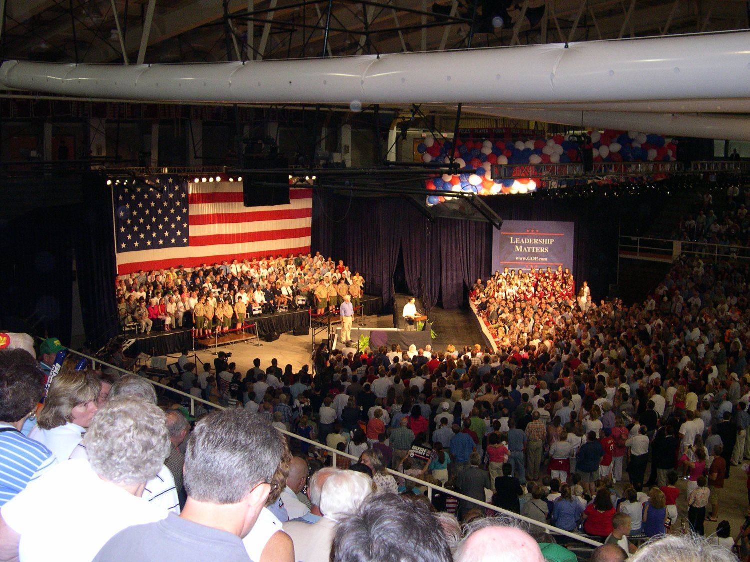 A large crowd of people watching a concert with an american flag in the background