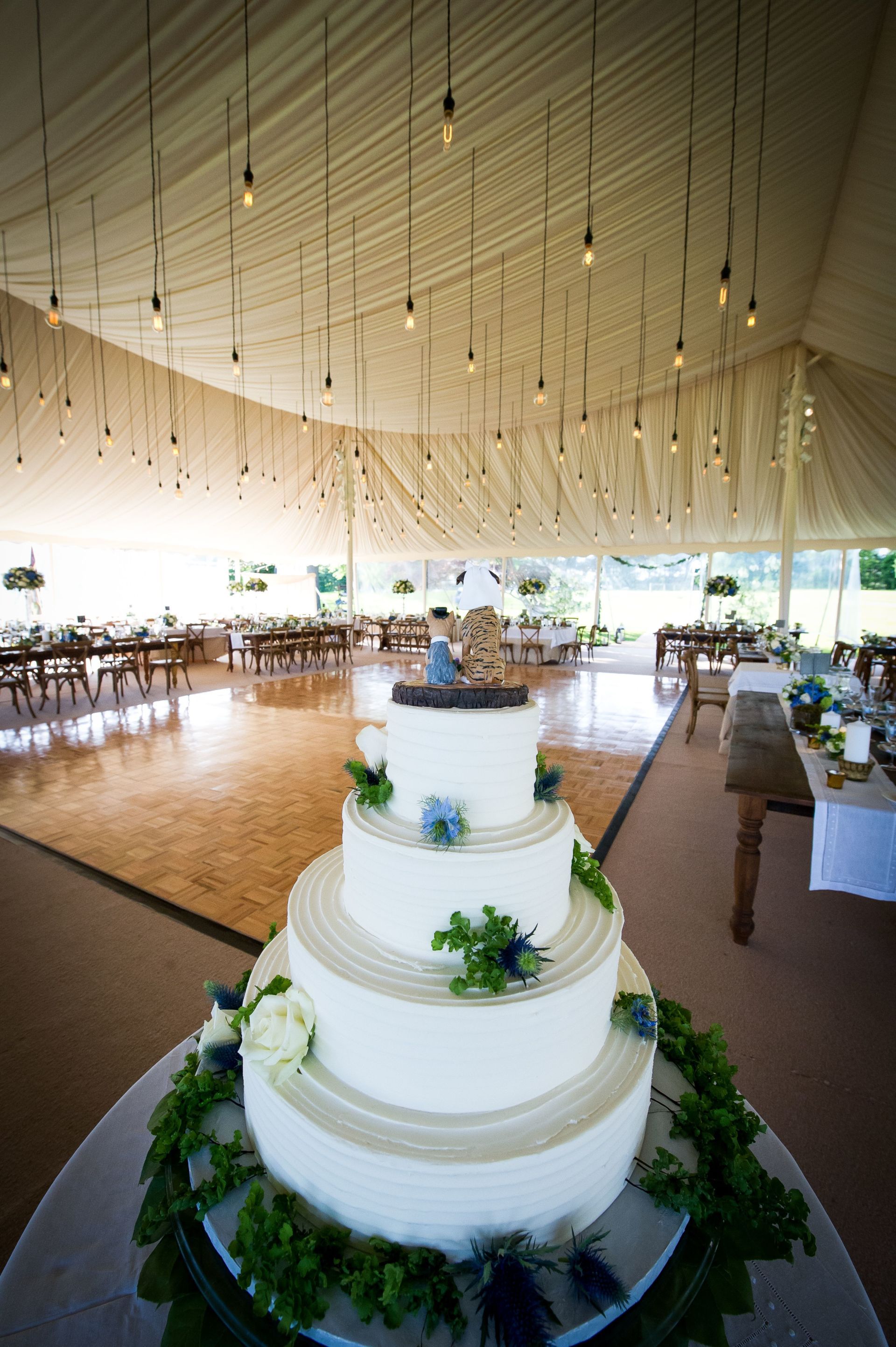 A wedding cake is sitting on a table in a tent.