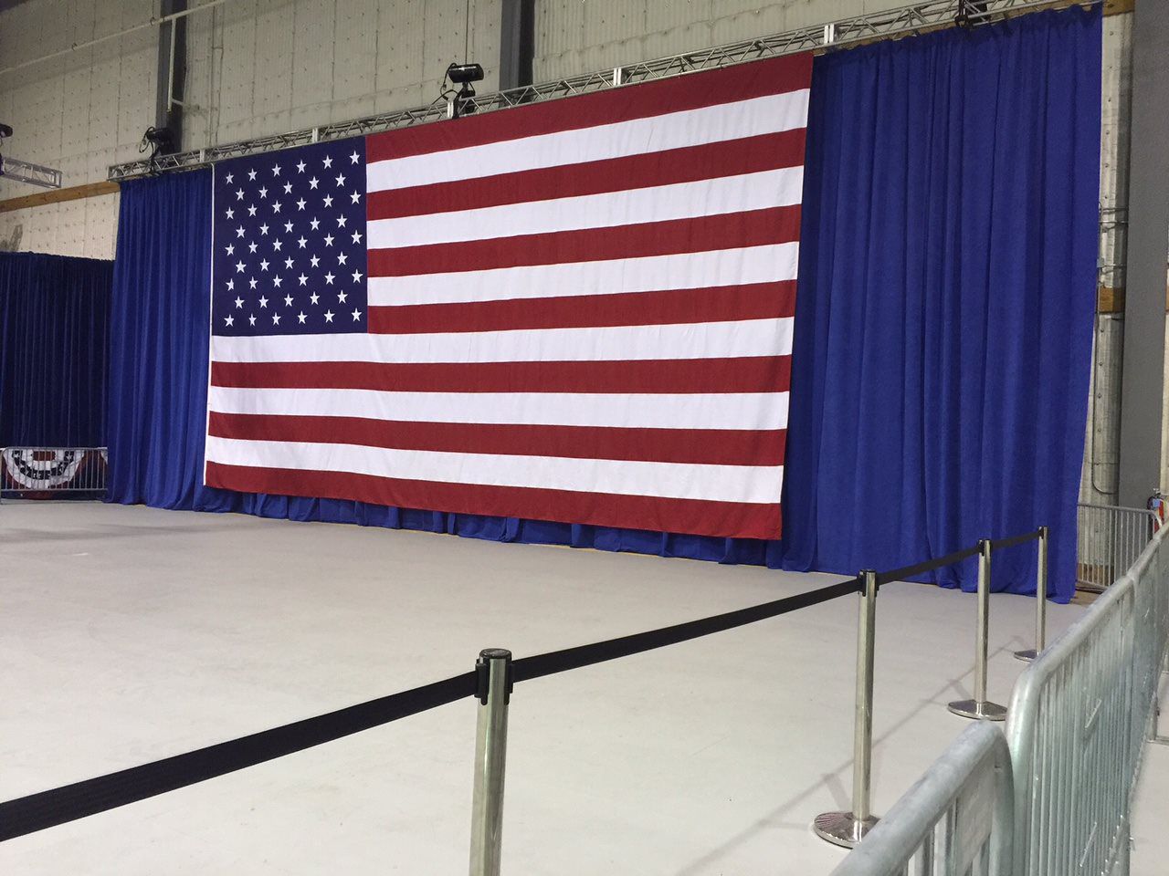 A large american flag is hanging on a wall behind a blue curtain.