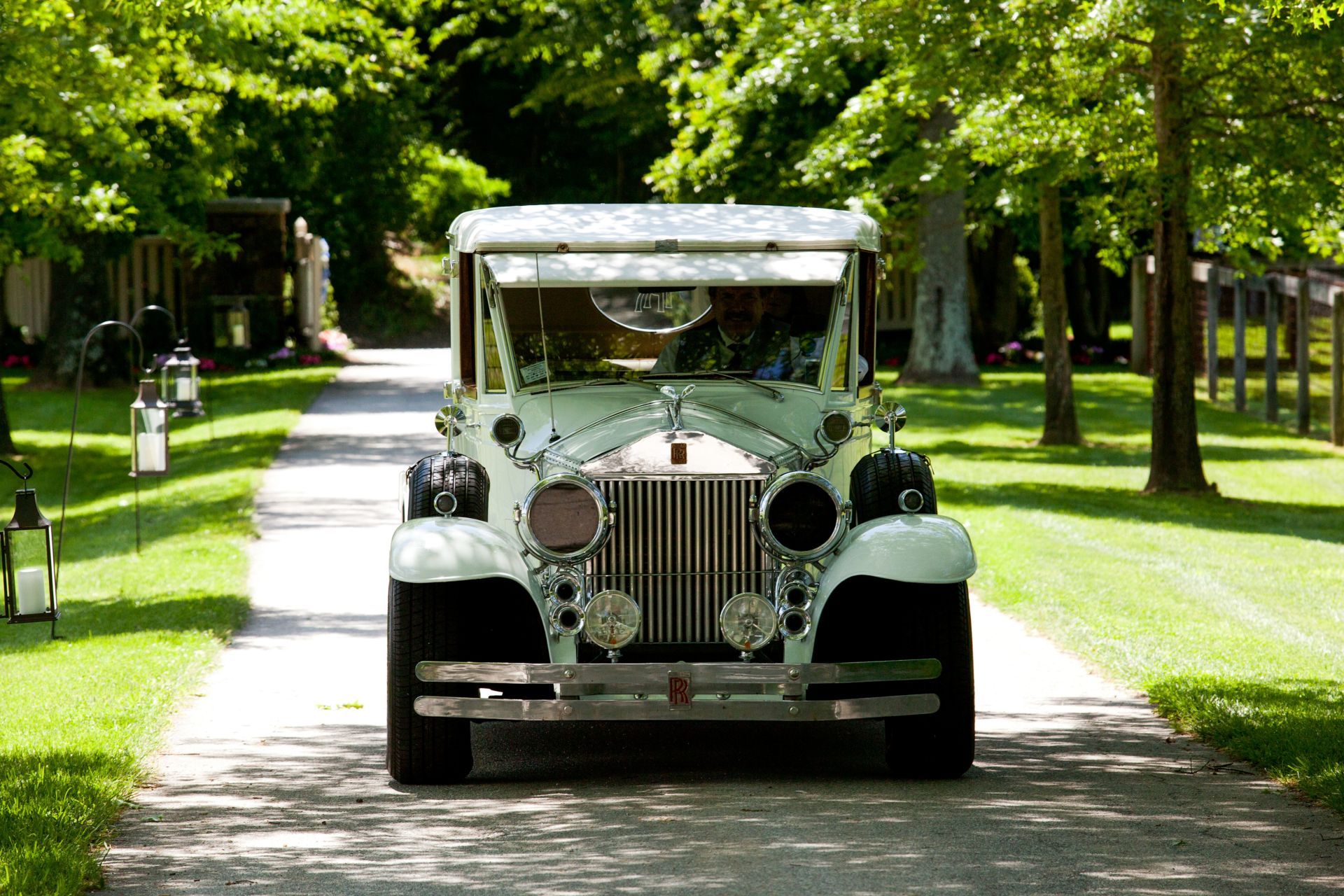 A white car is driving down a gravel road.