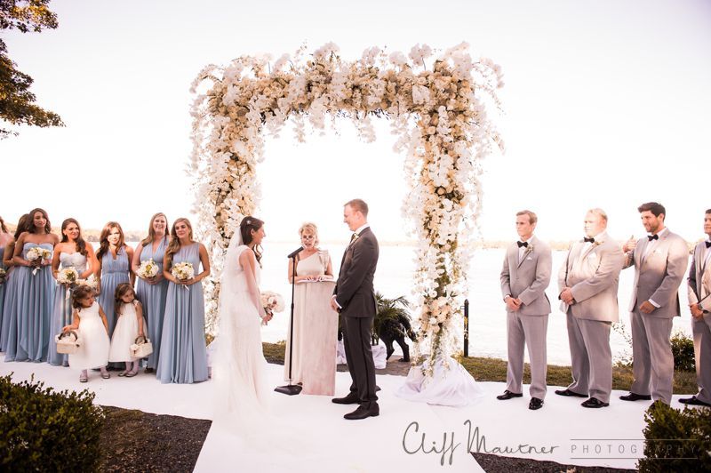 A bride and groom are getting married under a floral arch.