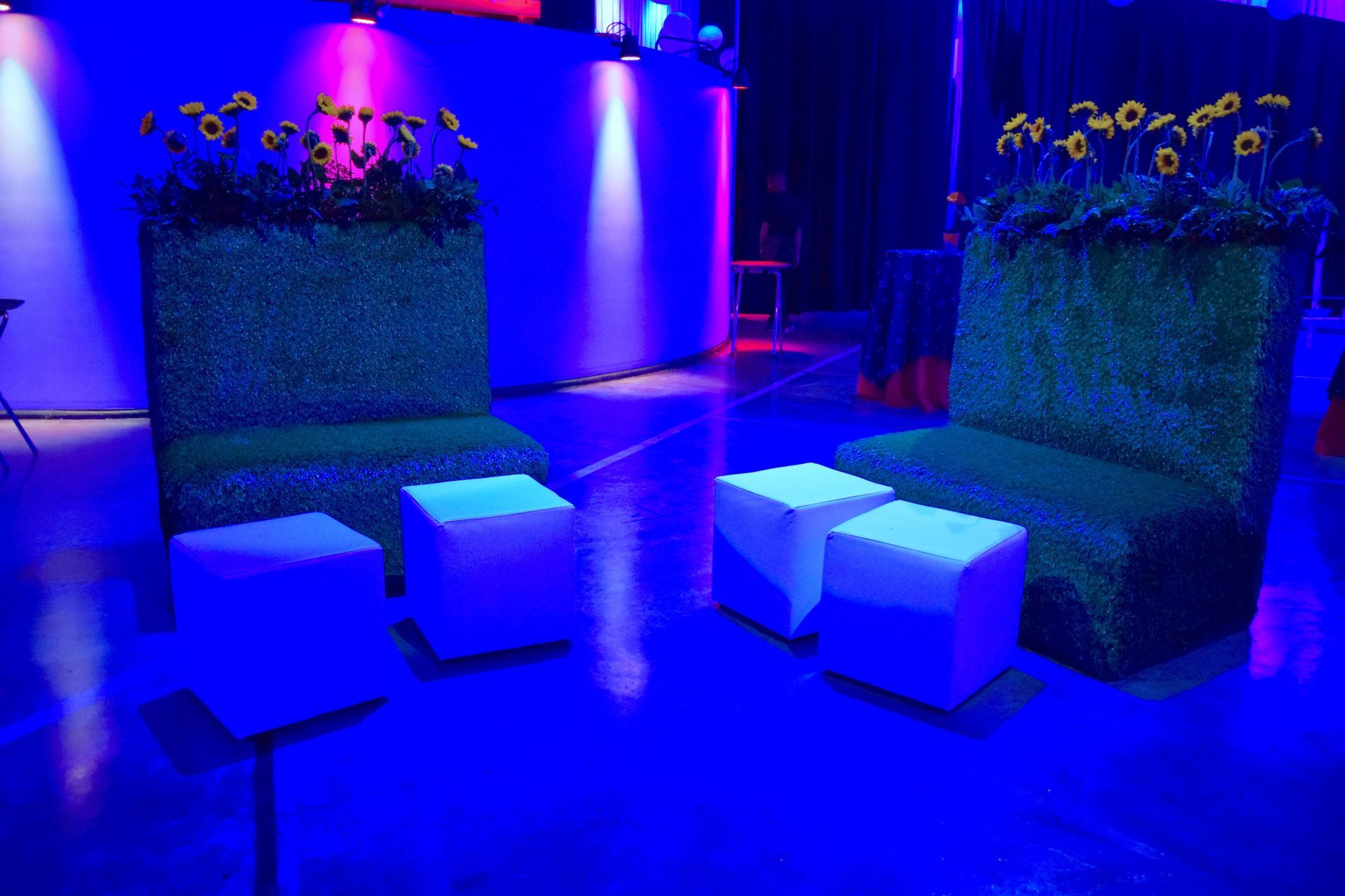 A couple of chairs and ottomans in a room with blue lights.
