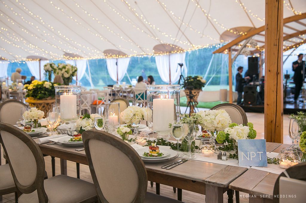 A large tent with tables and chairs set up for a wedding reception.