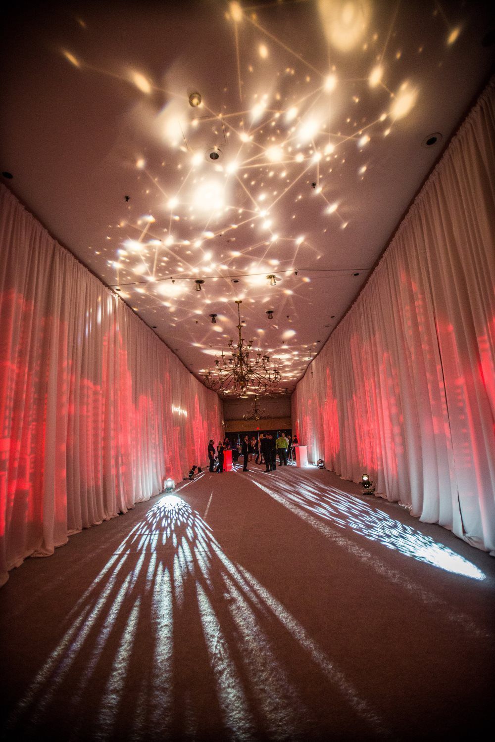 A long hallway with red curtains and lights on the ceiling.
