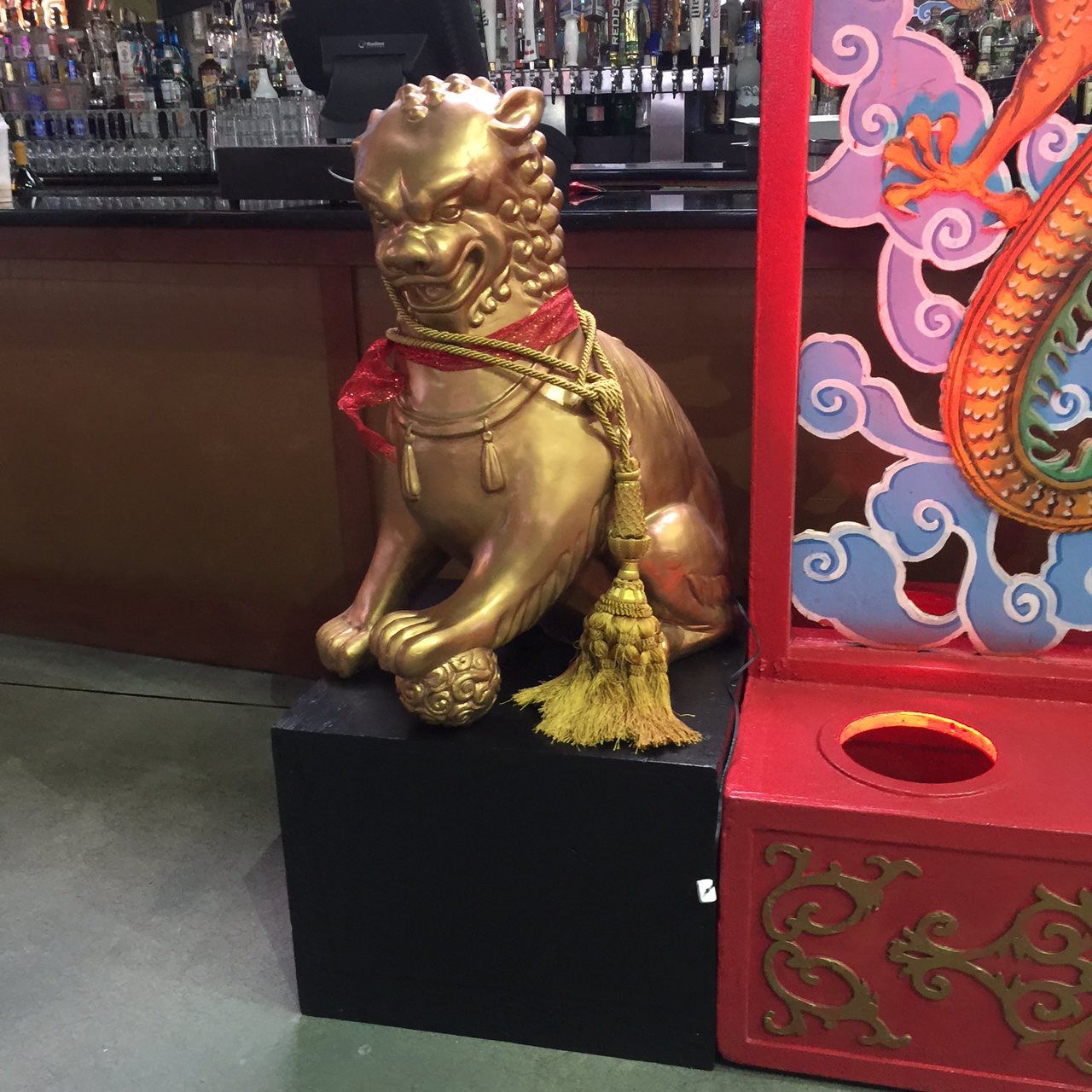 A gold statue of a lion with a red scarf around its neck
