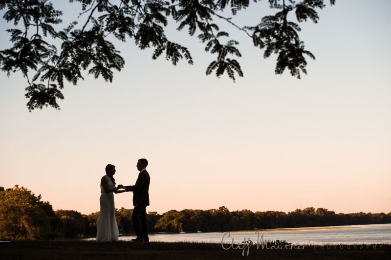 A bride and groom holding hands in front of a lake