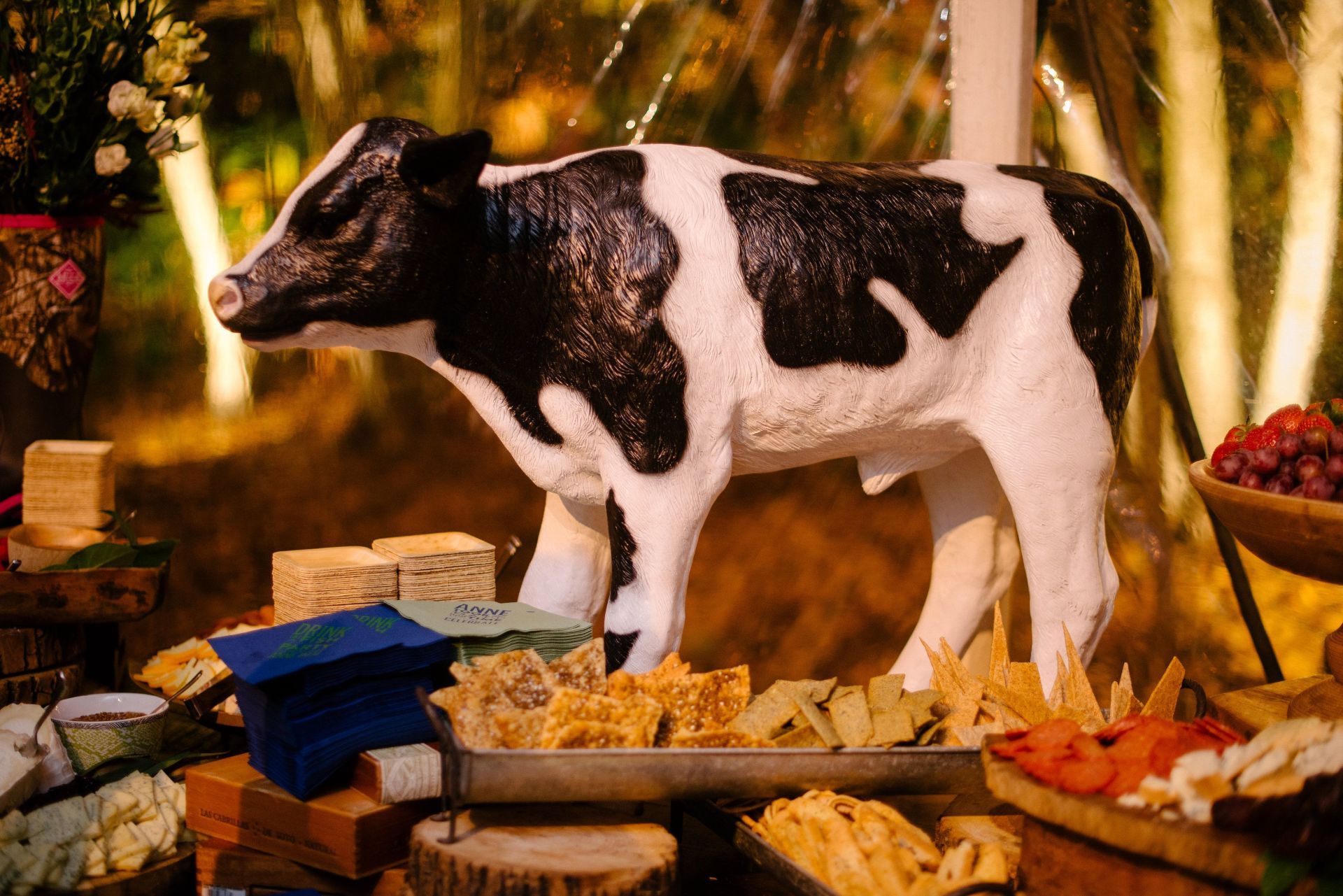 A statue of a cow is sitting on a table with food.
