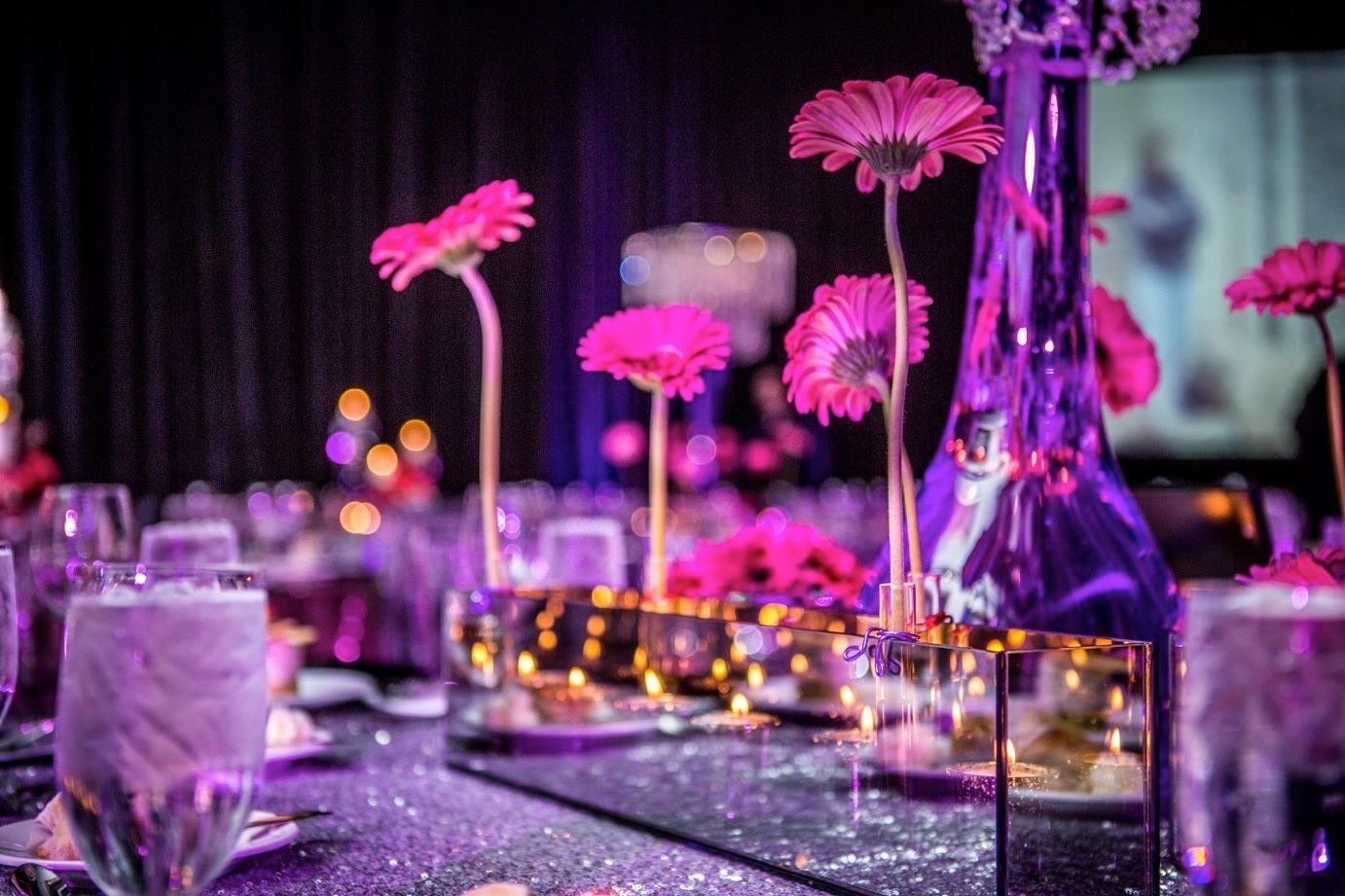 A table set for a party with purple flowers in vases.