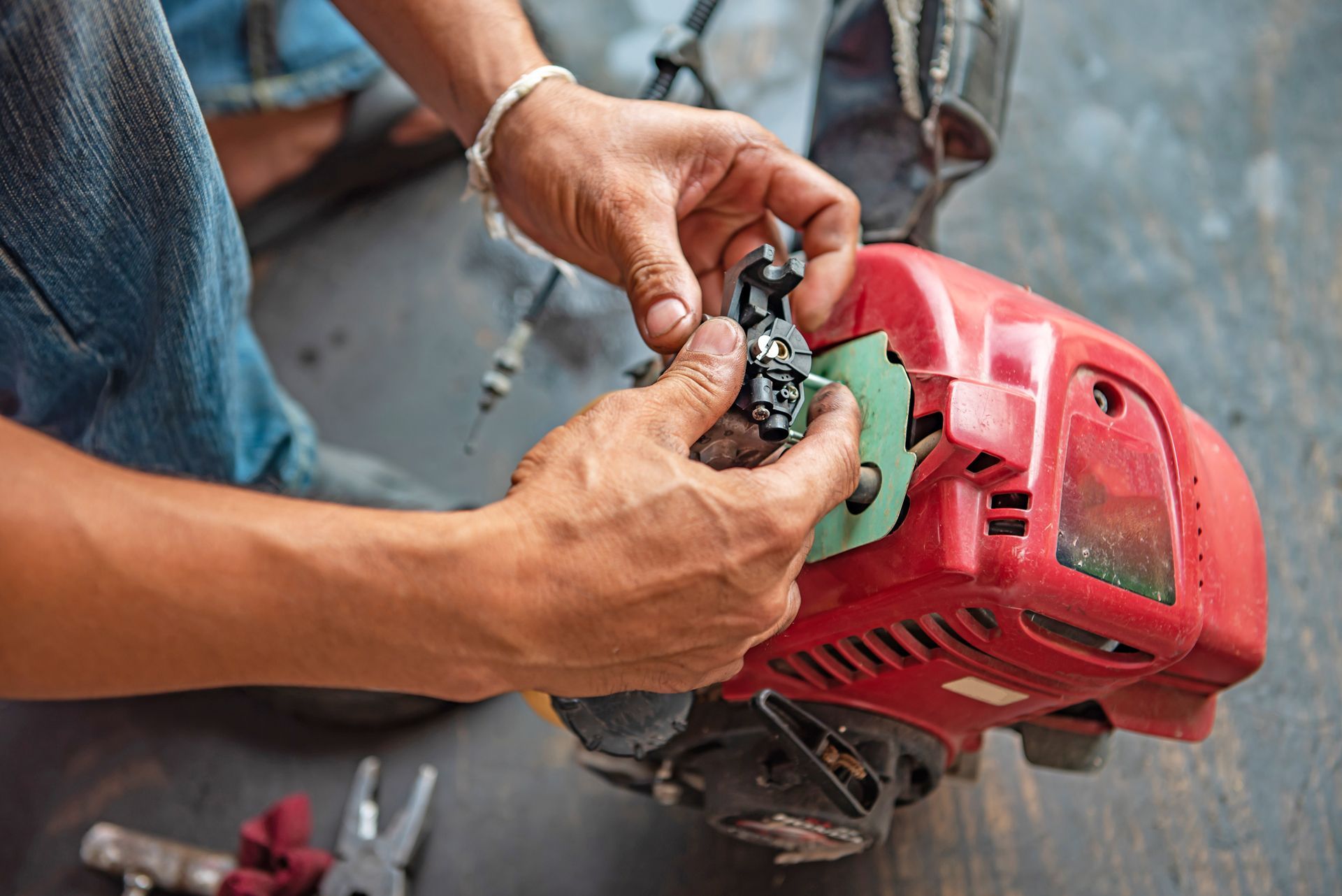 Person working on a red engine; hands holding a black component.