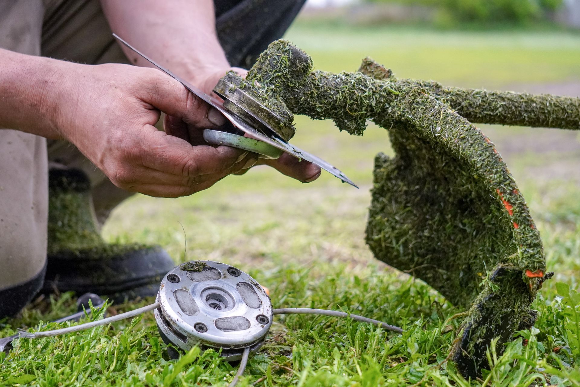 Person changing the blade on a weed wacker outdoors.